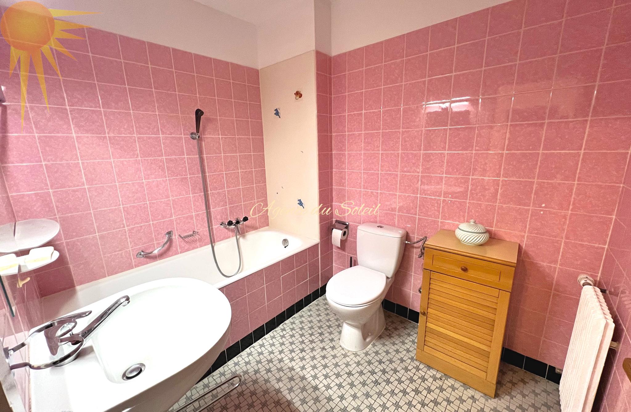 Rosa gefliestes Badezimmer mit Badewanne und WC