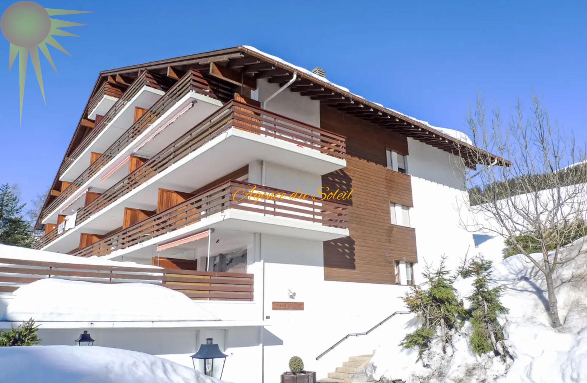 Außenansicht eines Chalet-Mehrfamilienhauses im Schnee