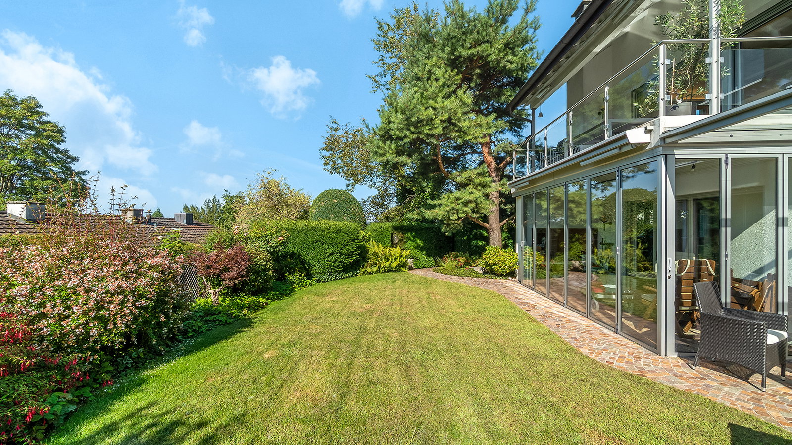 Moderner Garten mit glasverkleidetem Haus