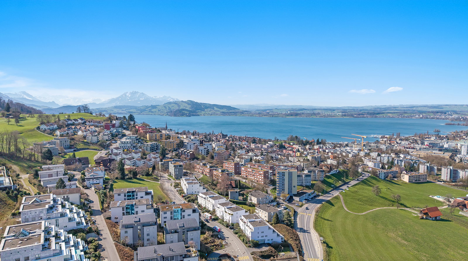 Luftaufnahme einer Stadt am See mit Alpenpanorama