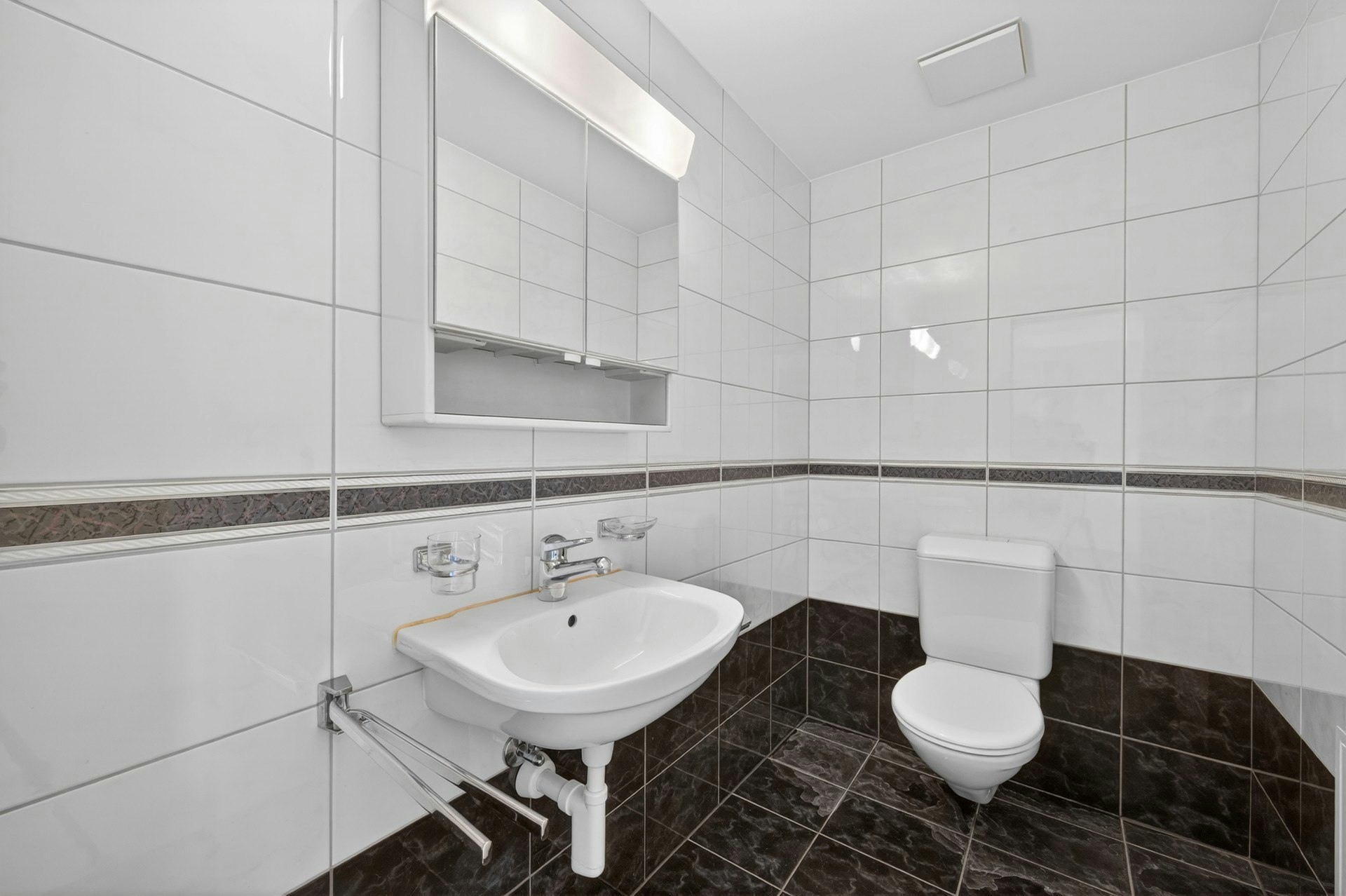 Kleines, modern gefliestes Badezimmer mit WC und Waschbecken