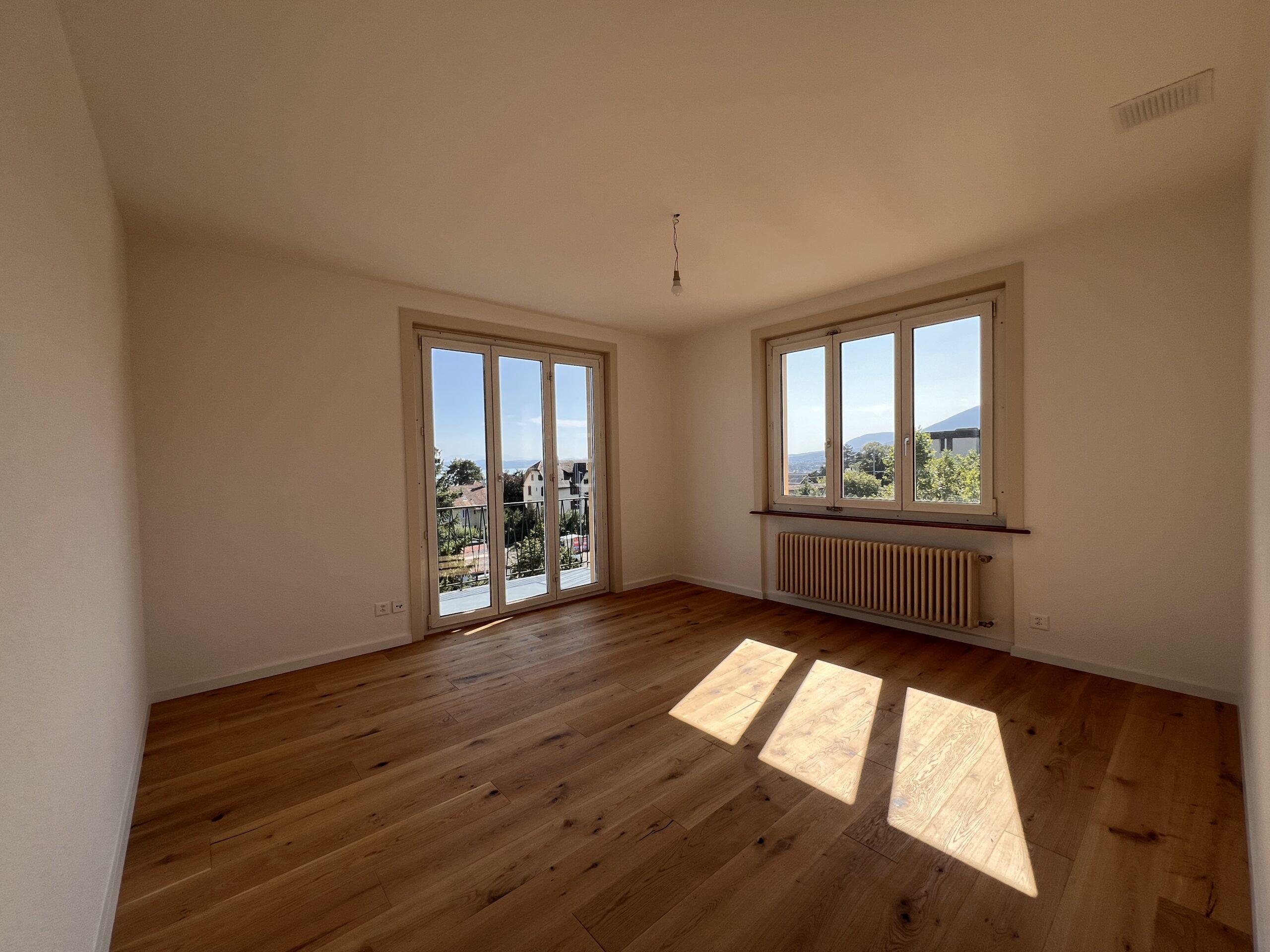 Leerer, sonniger Wohnraum mit zwei Fenstern