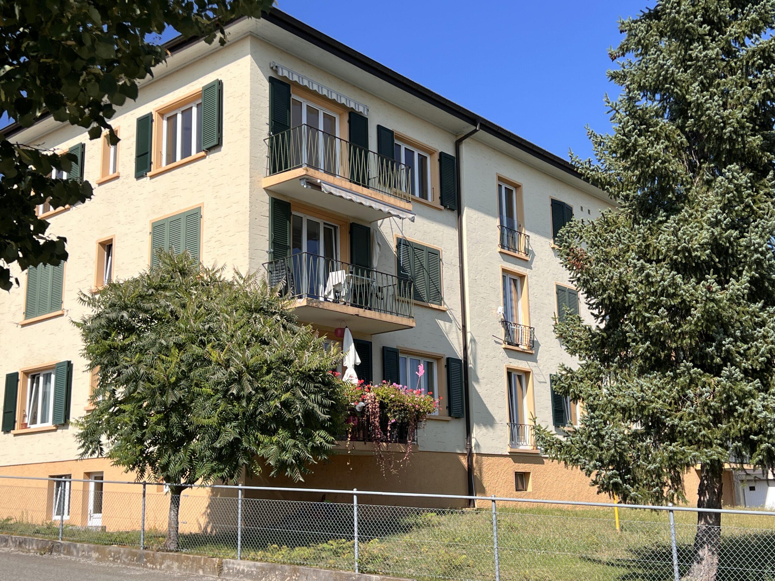 Mehrfamilienhaus mit Balkonen und grüner Fensterläden