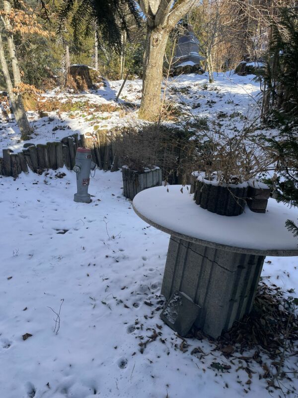Verschneiter Garten mit rundem Tisch und Hydranten