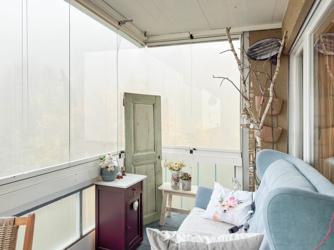 Gemütlicher verglaster Balkon mit Sitzbereich