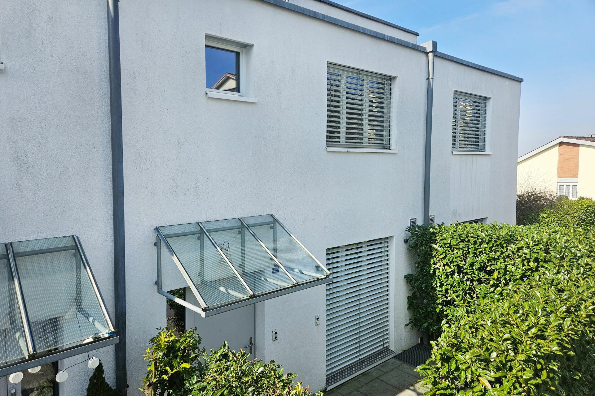 Weiße moderne Außenfassade mit Fenstern und Gartenbereich