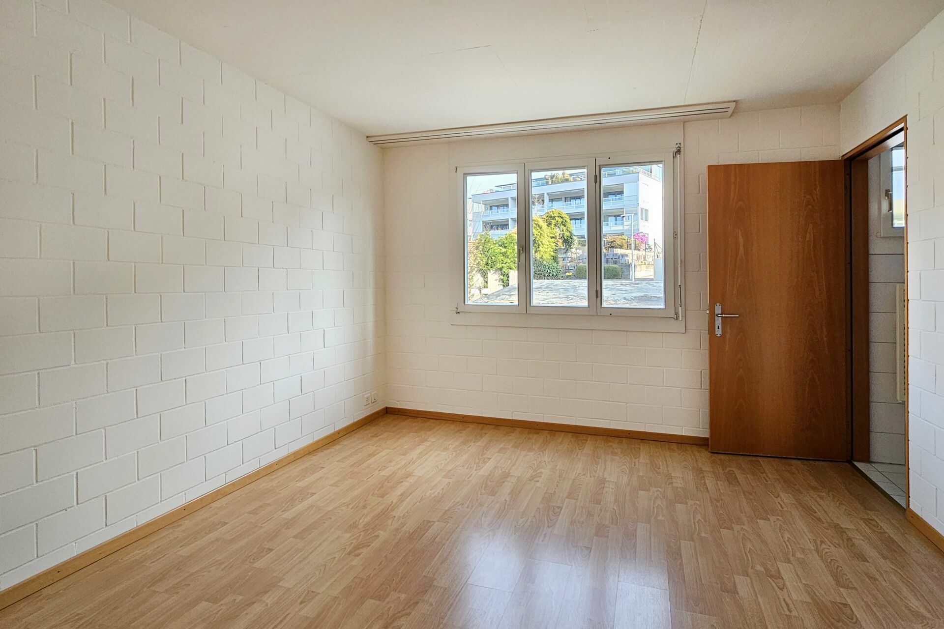 Heller, leerer Raum mit Fenster und Holztür