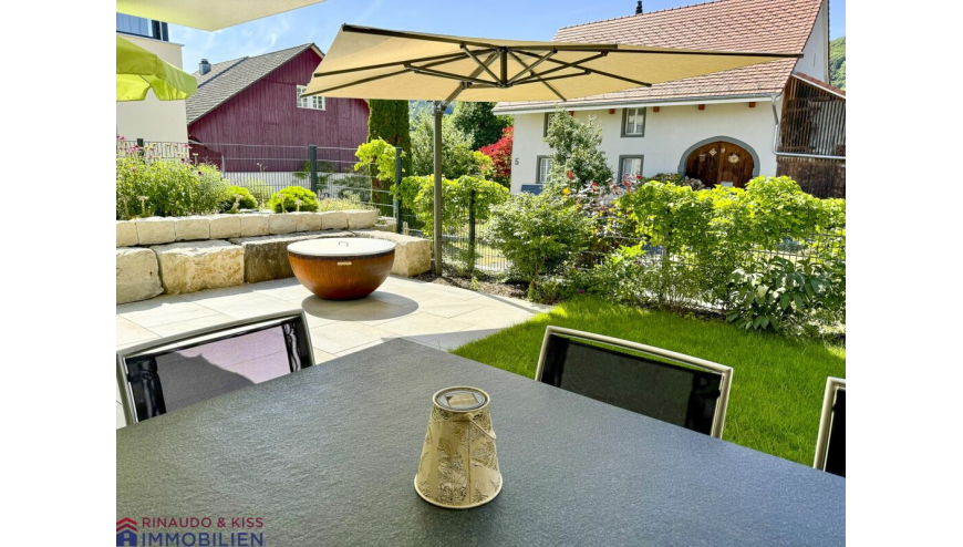 Gepflegte Terrasse mit Garten und Blick auf Wohnhaus