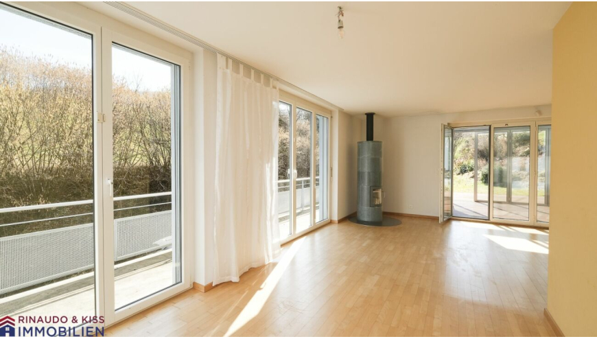 Heller Wohnraum mit großen Fenstern und Holzofen