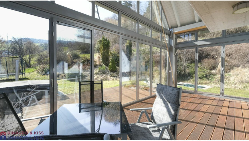 Verglaster Wintergarten mit Terrasse und Gartenblick