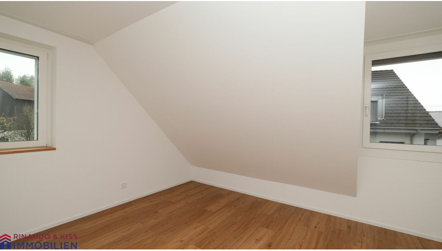Dachzimmer mit Holzboden und zwei Fenstern