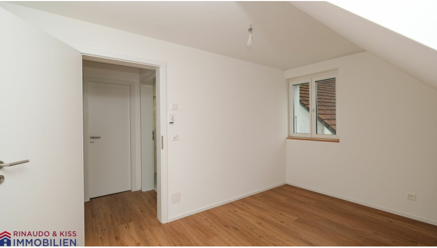 Leerer Dachraum mit Fenster und Holzfußboden