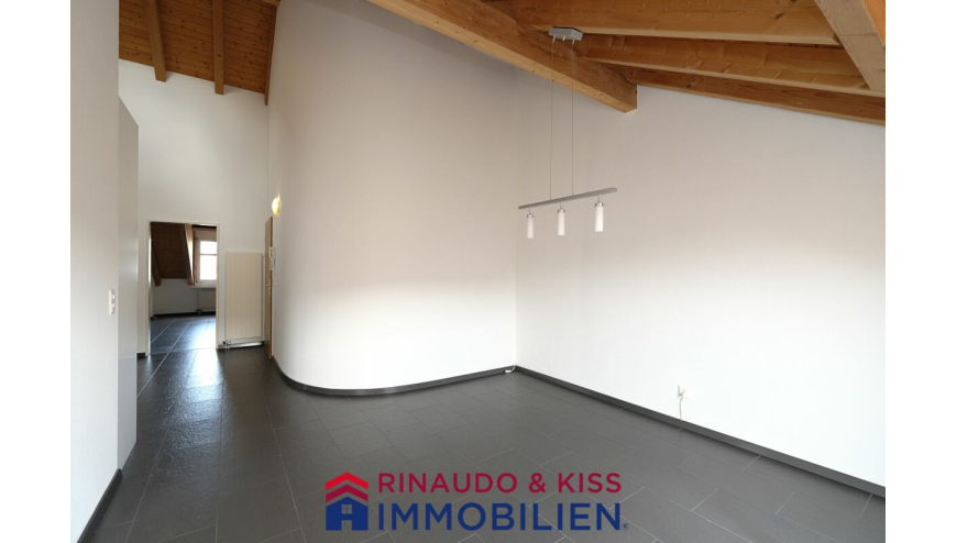 Leerer Wohnraum mit sichtbarer Holzbalkendecke