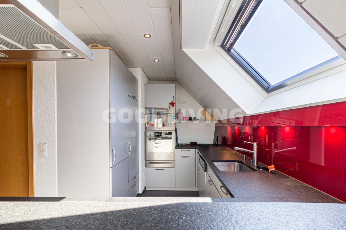 Dachküche mit Dachfenster und roten Glasrückwänden