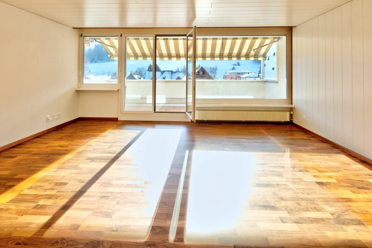 Heller leerer Wohnraum mit Balkon und Winterblick