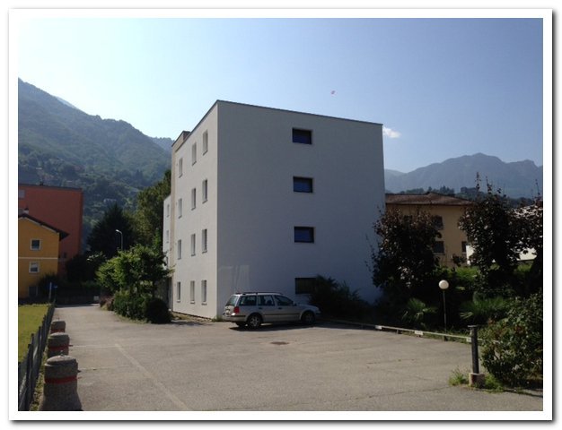 Mehrfamilienhaus mit Parkplatz und Bergkulisse