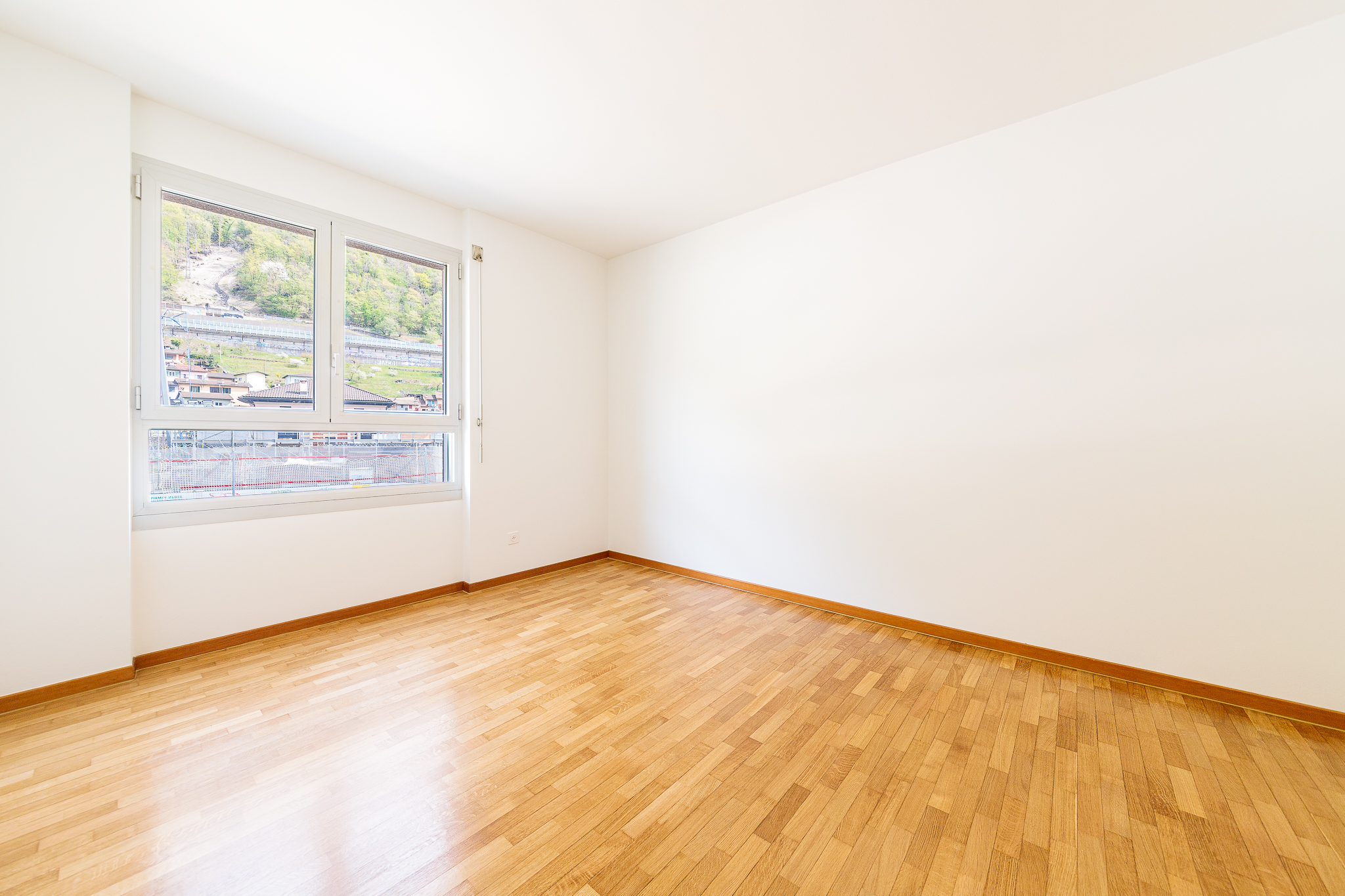 Heller leerer Raum mit Holzparkett und Fensterblick