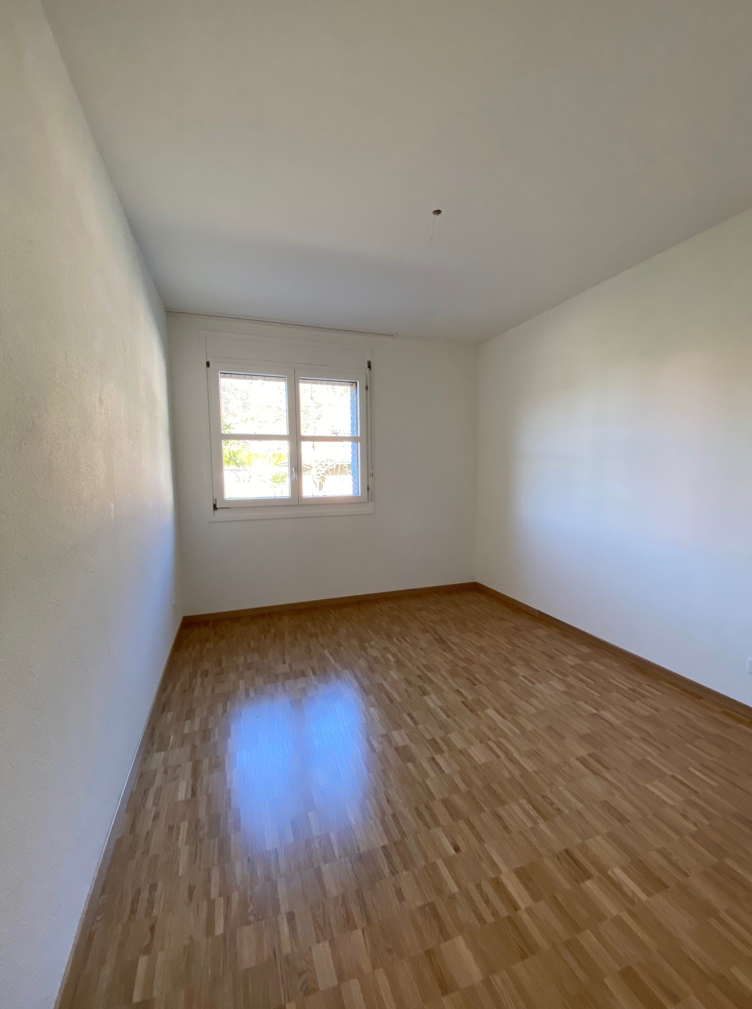 Leerer, heller Raum mit Parkett und Fenster