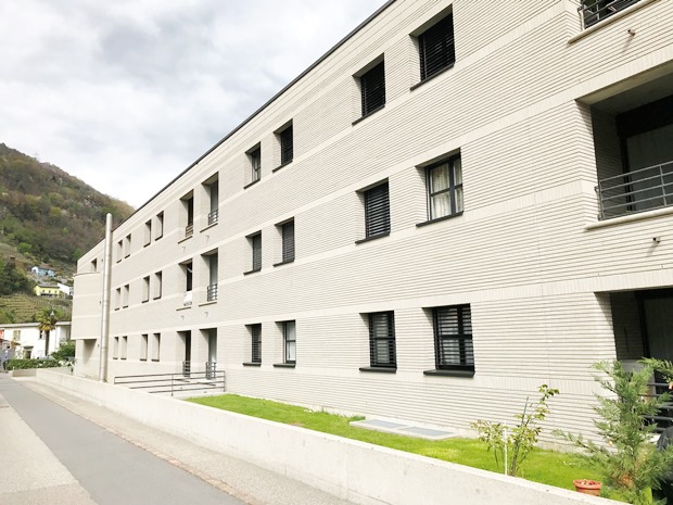 Mehrfamilienhaus mit heller Fassade entlang einer Straße