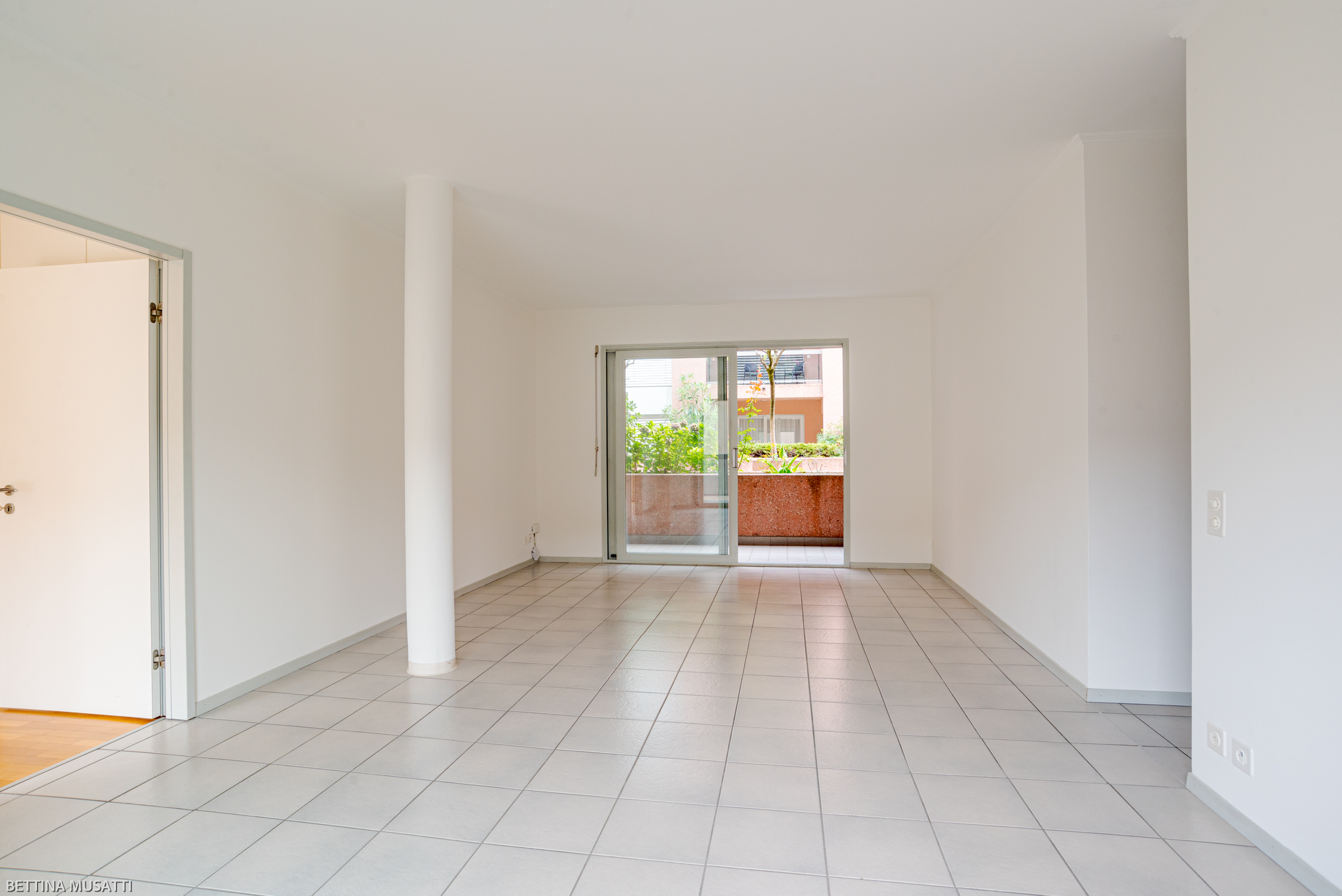 Leerer Wohnraum mit Zugang zum Balkon