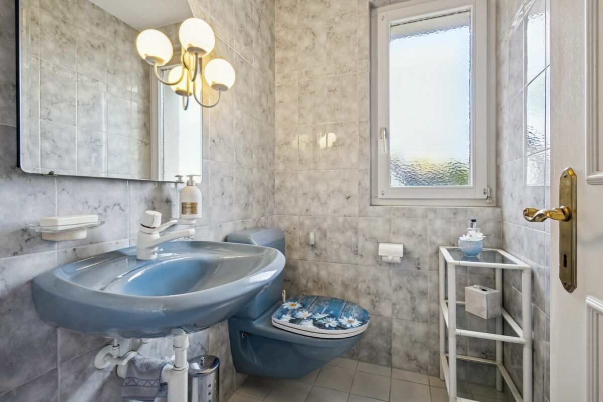 Helles Gäste-WC mit blauem Waschtisch und Marmoroptik