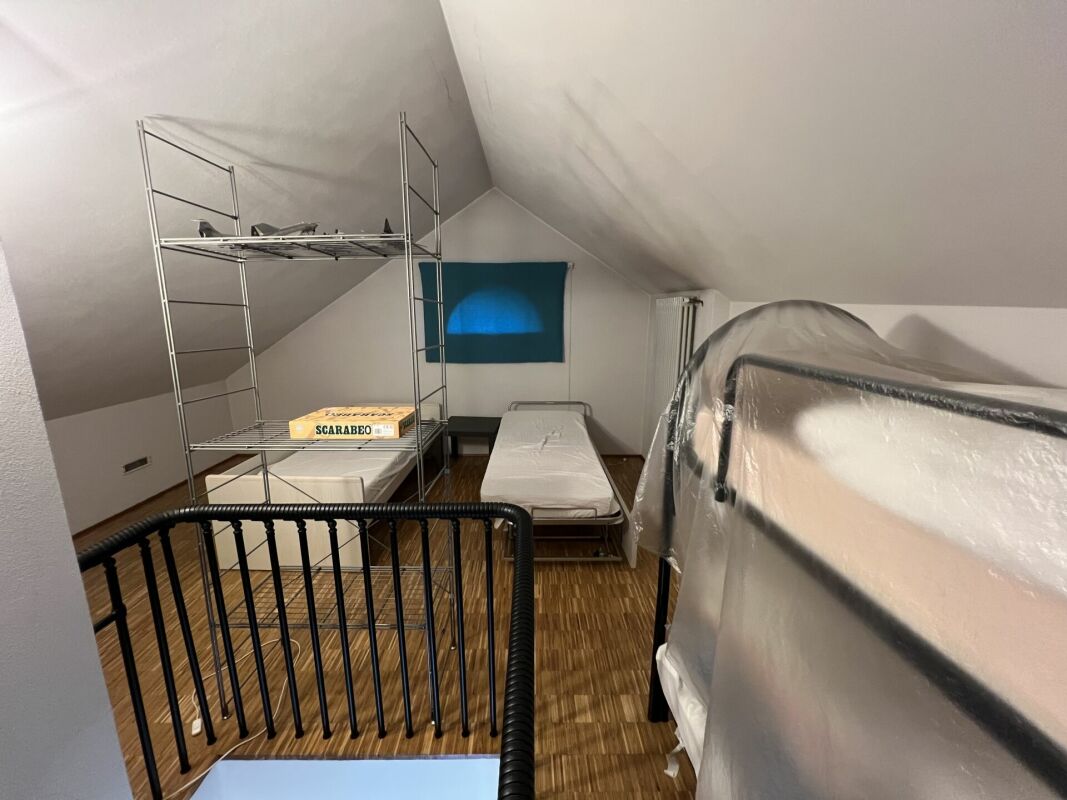 Dachzimmer mit Schlafplätzen und Metallregalen