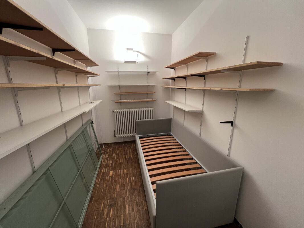 Ankleidezimmer mit offenen Regalen und Bettgestell