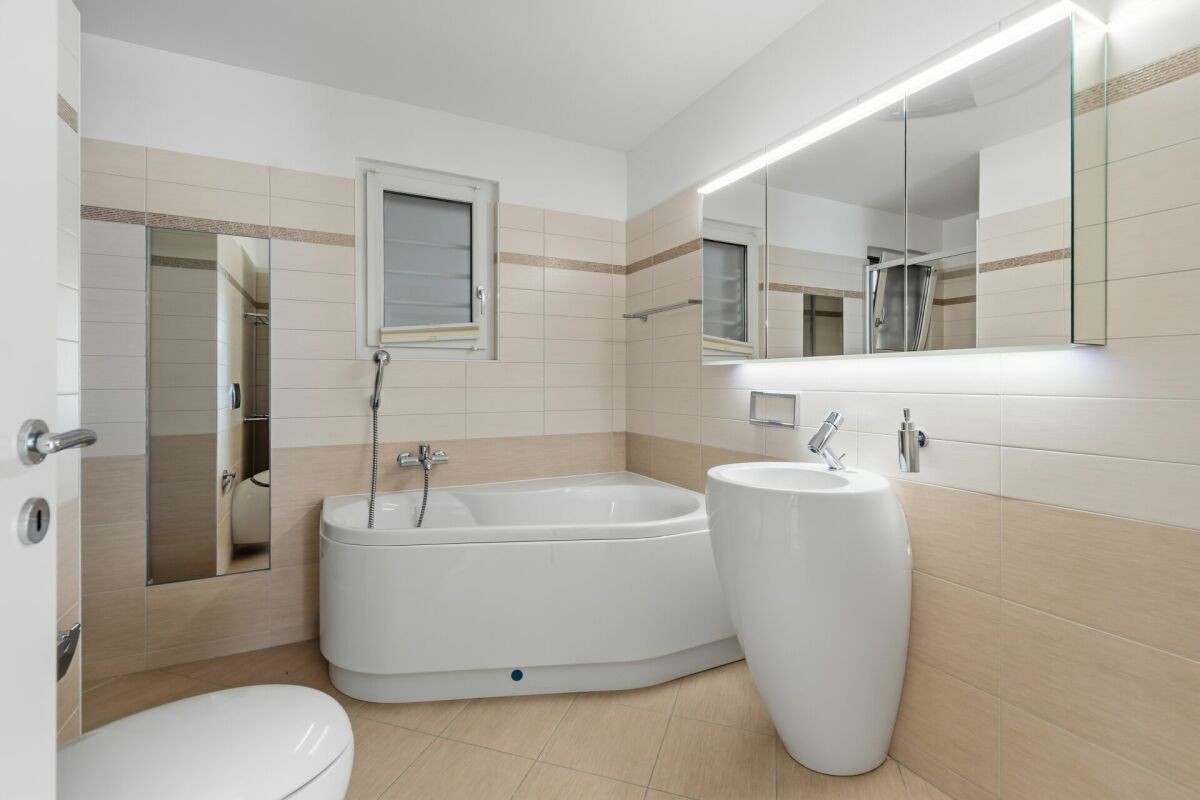Modernes Badezimmer mit Badewanne und beleuchtetem Spiegelschrank