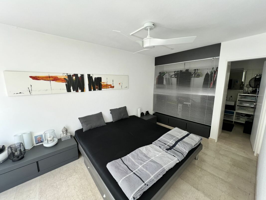 Modernes Schlafzimmer mit dunklem Bett und großem Schrankbereich