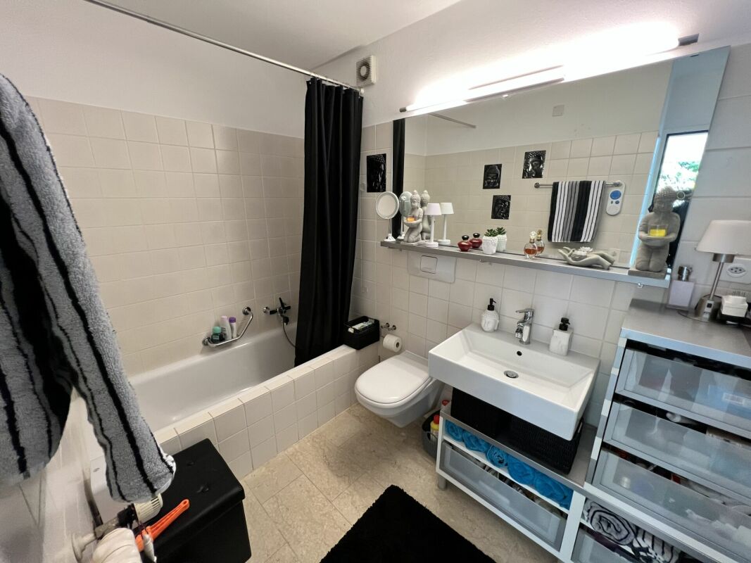 Modernes Badezimmer mit Badewanne, Waschtisch und großem Spiegel