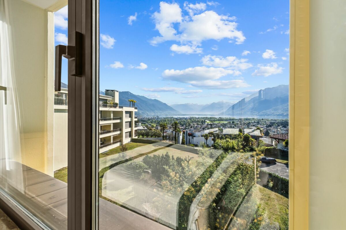 Blick durch ein Fenster auf See und Berge