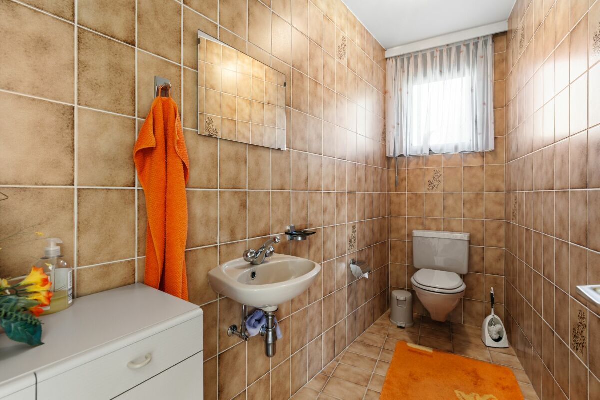Gäste-WC mit orangefarbenen Akzenten