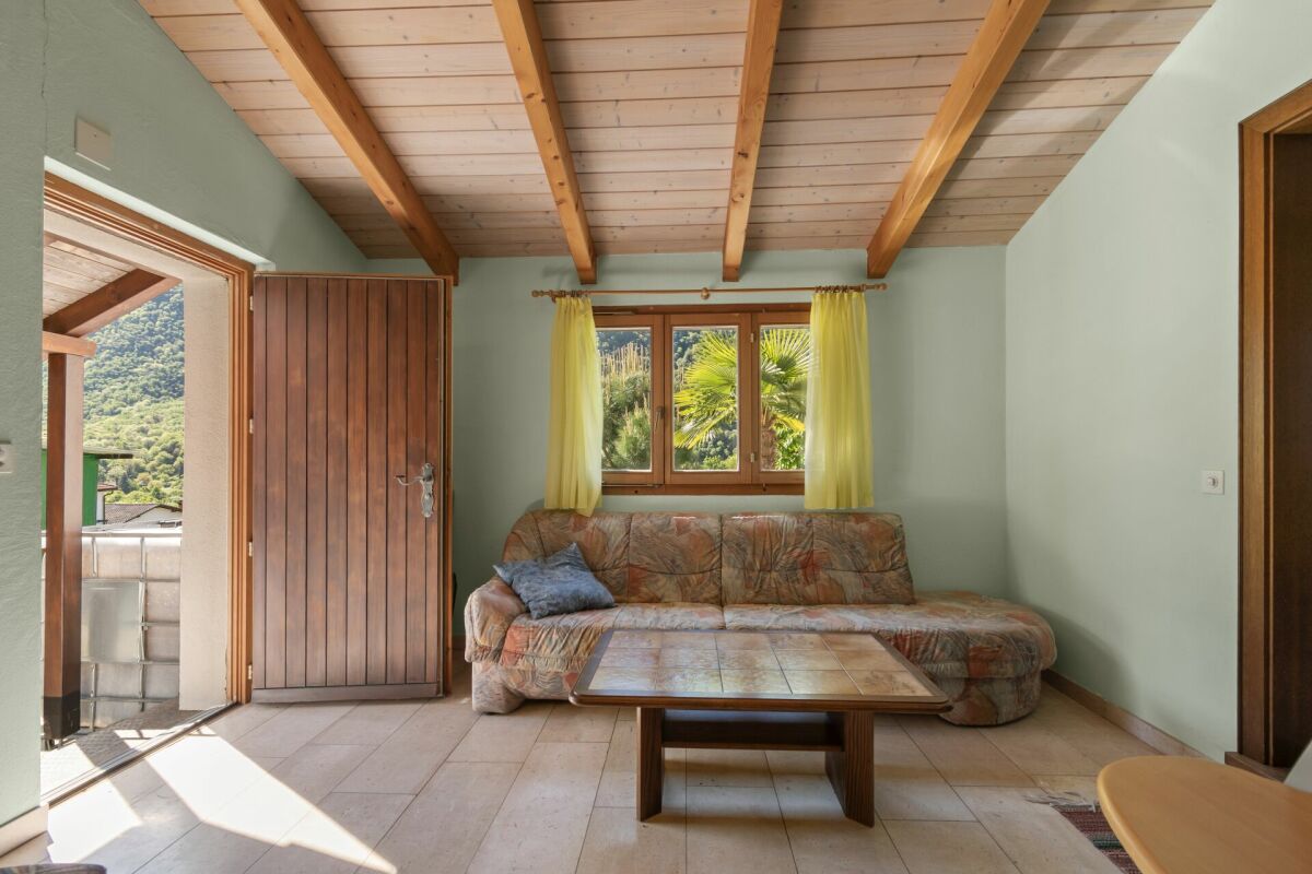 Wohnzimmer mit Holzbalkendecke und Balkonzugang