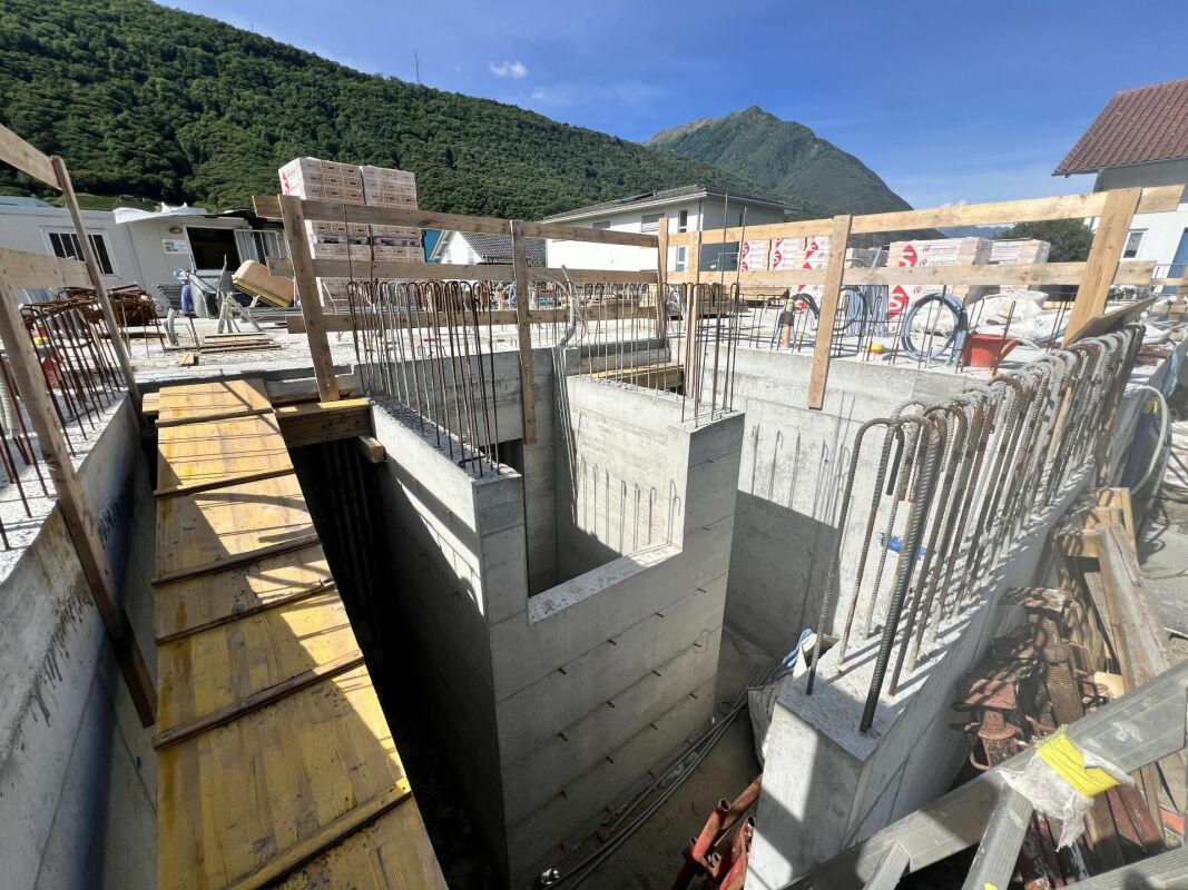 Baustelle mit Stahlbeton-Kellergeschoss und Bergkulisse