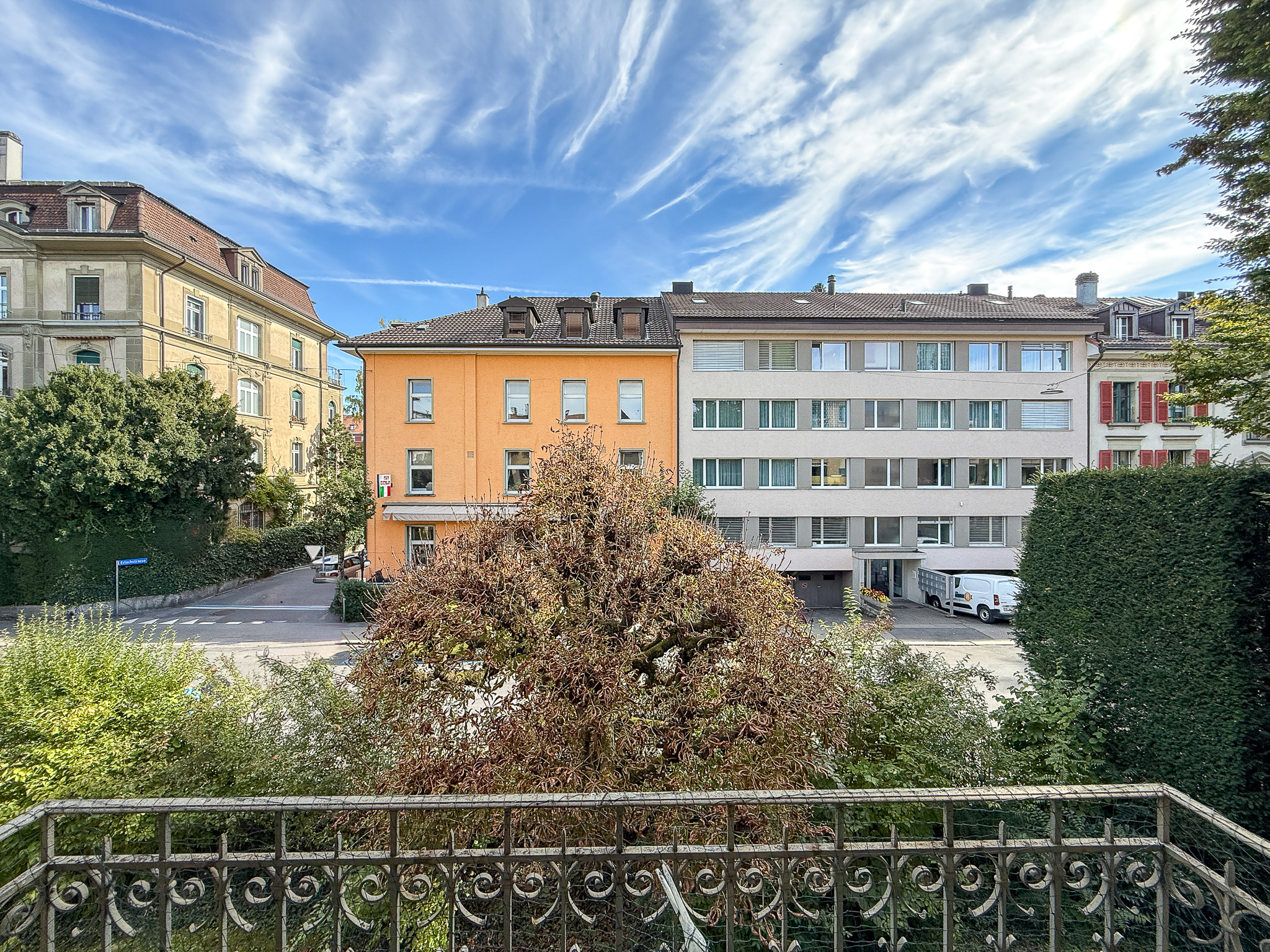 Blick vom Balkon auf Wohnhäuser und Straßenbegrünung