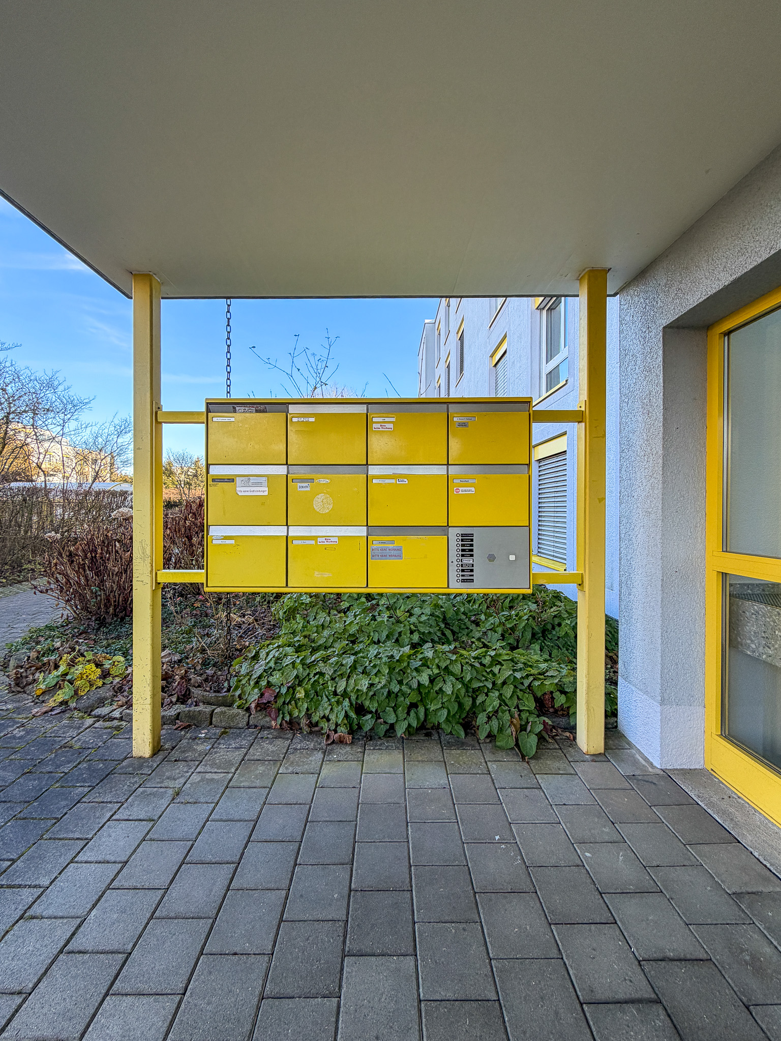 Außenbereich mit gelber Briefkastenanlage