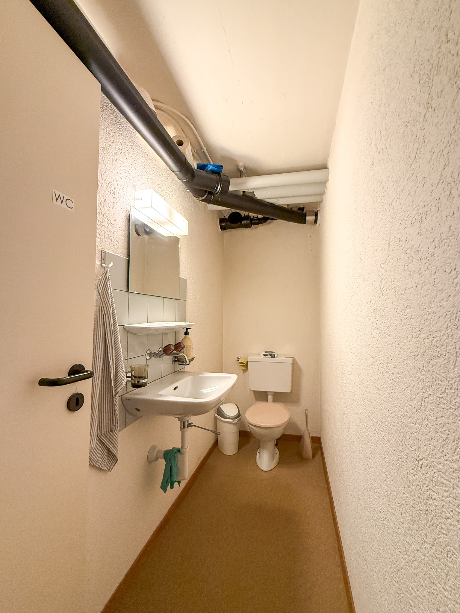 Kleines WC mit sichtbaren Leitungen