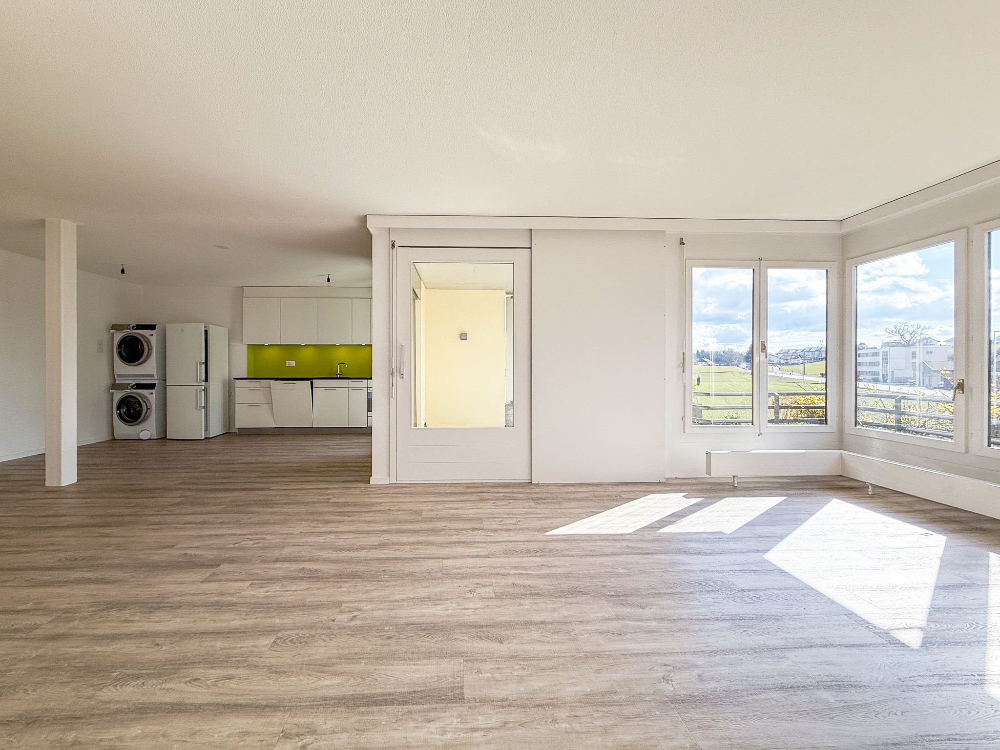 Offener Wohnbereich mit Küche und großen Fenstern