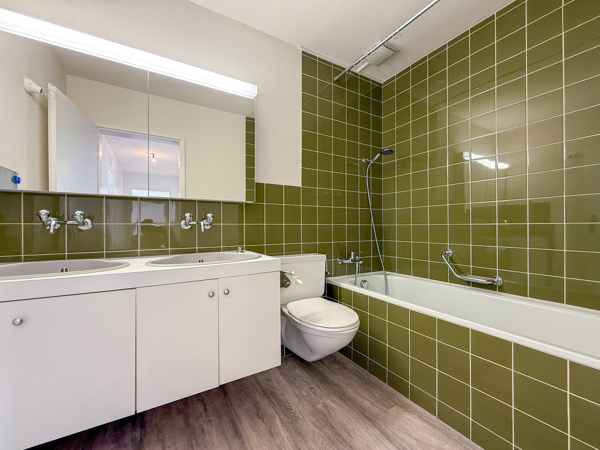 Badezimmer mit grünen Fliesen und Wannenbereich