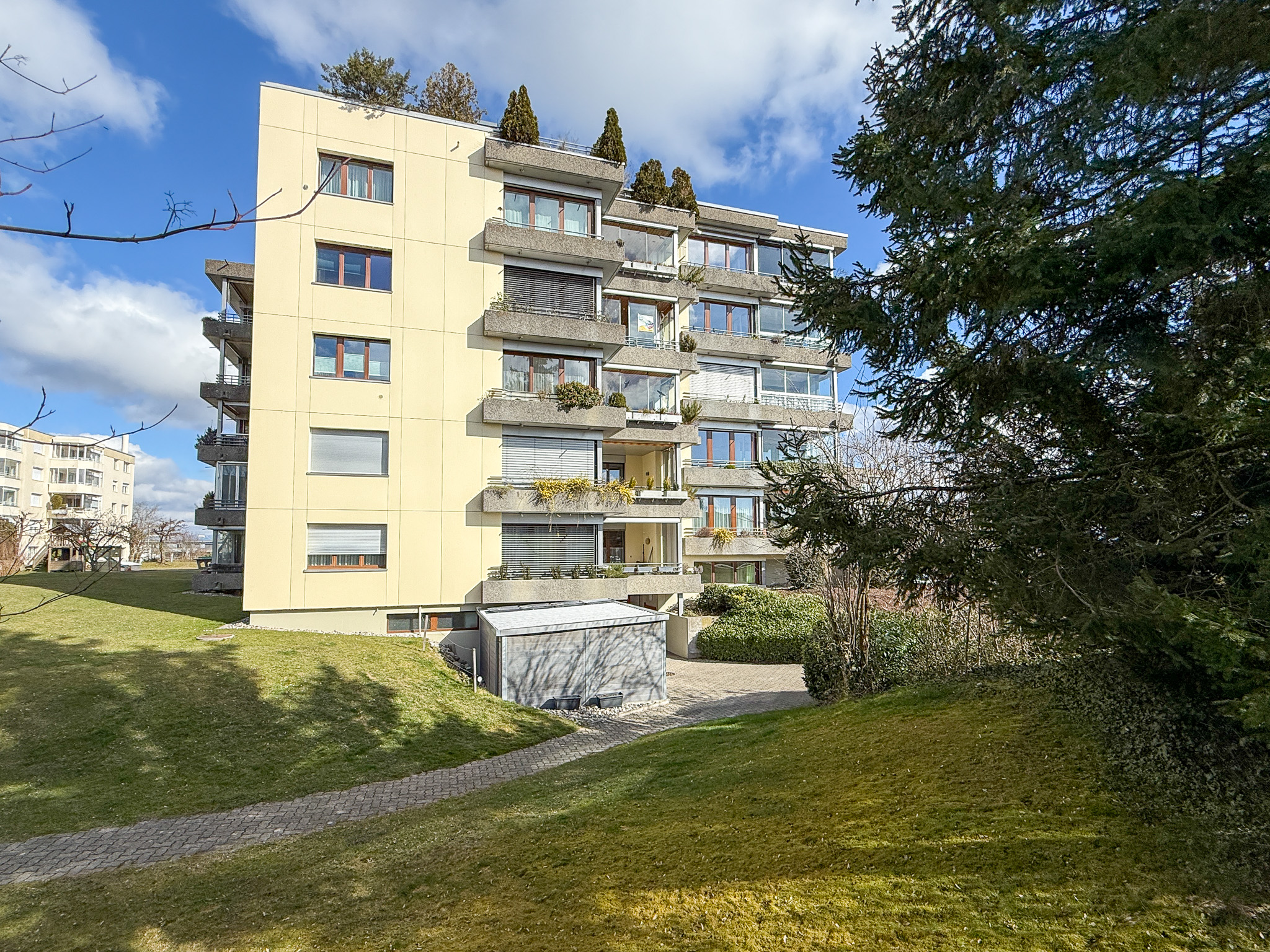 Mehrfamilienhaus mit Balkonen in grüner Umgebung