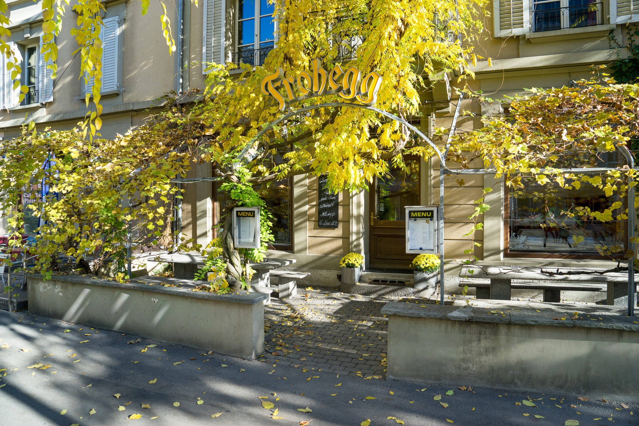 Außenansicht eines begrünten Erdgeschosses mit Restaurant-/Café-Eingang