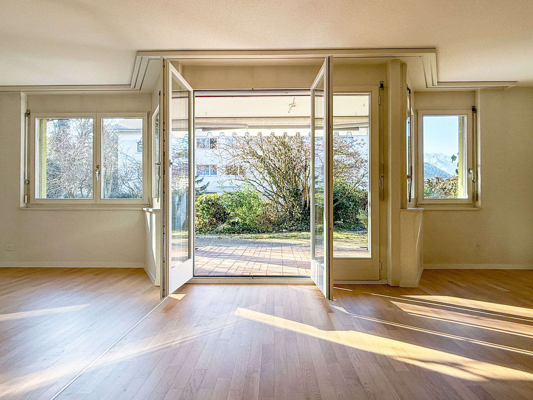 Helles Zimmer mit großen Fenstern und Gartenzugang