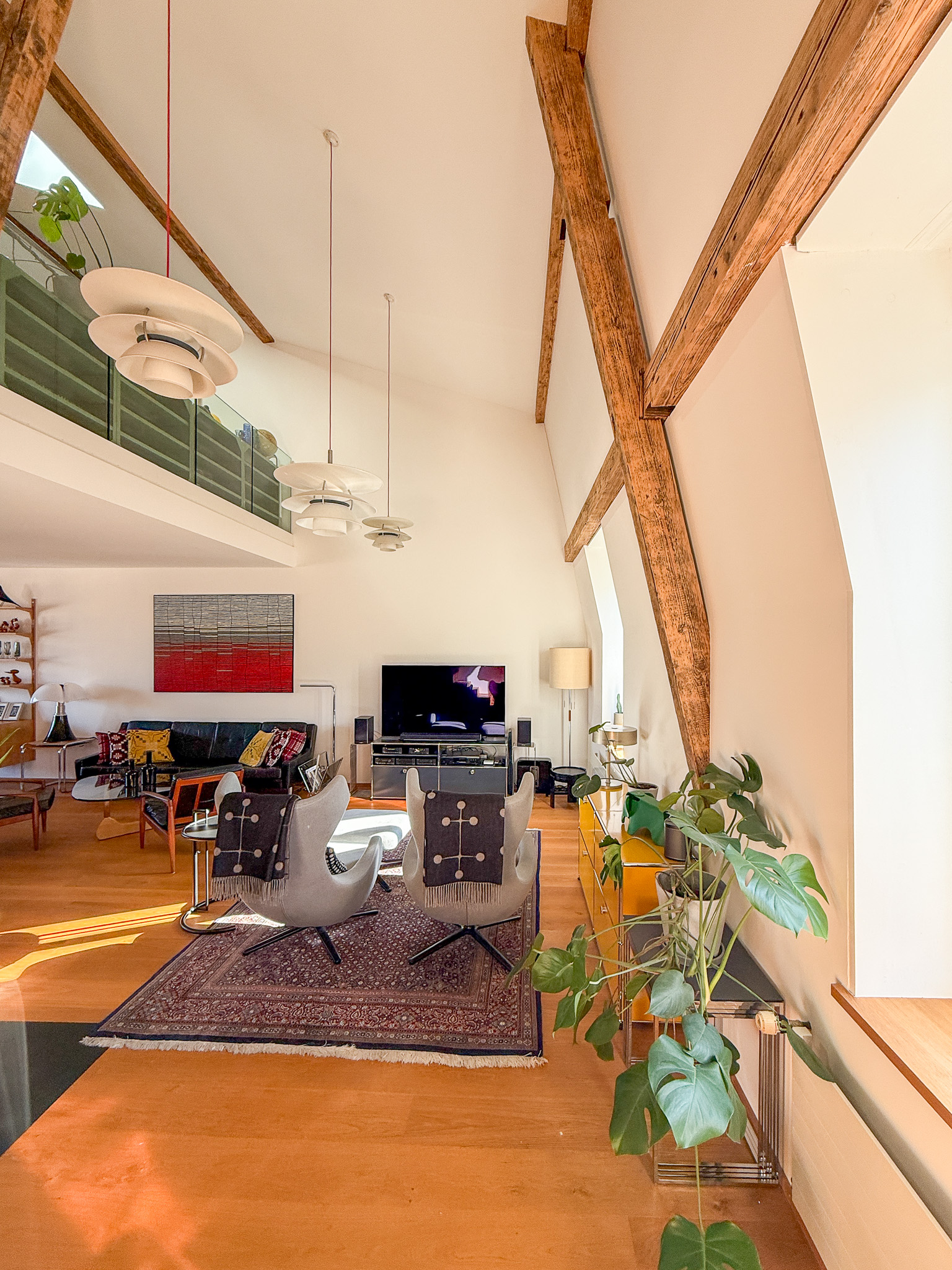 Offener Wohnbereich mit hoher Decke und sichtbaren Holzbalken