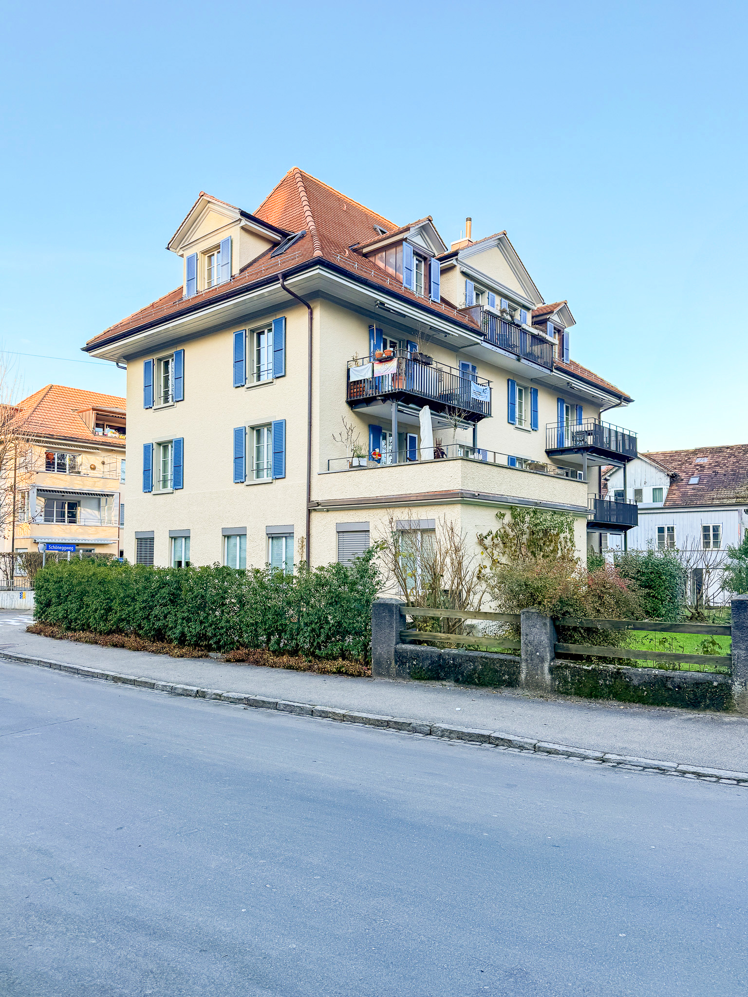Mehrfamilienhaus mit roten Ziegeldächern und blauen Fensterläden