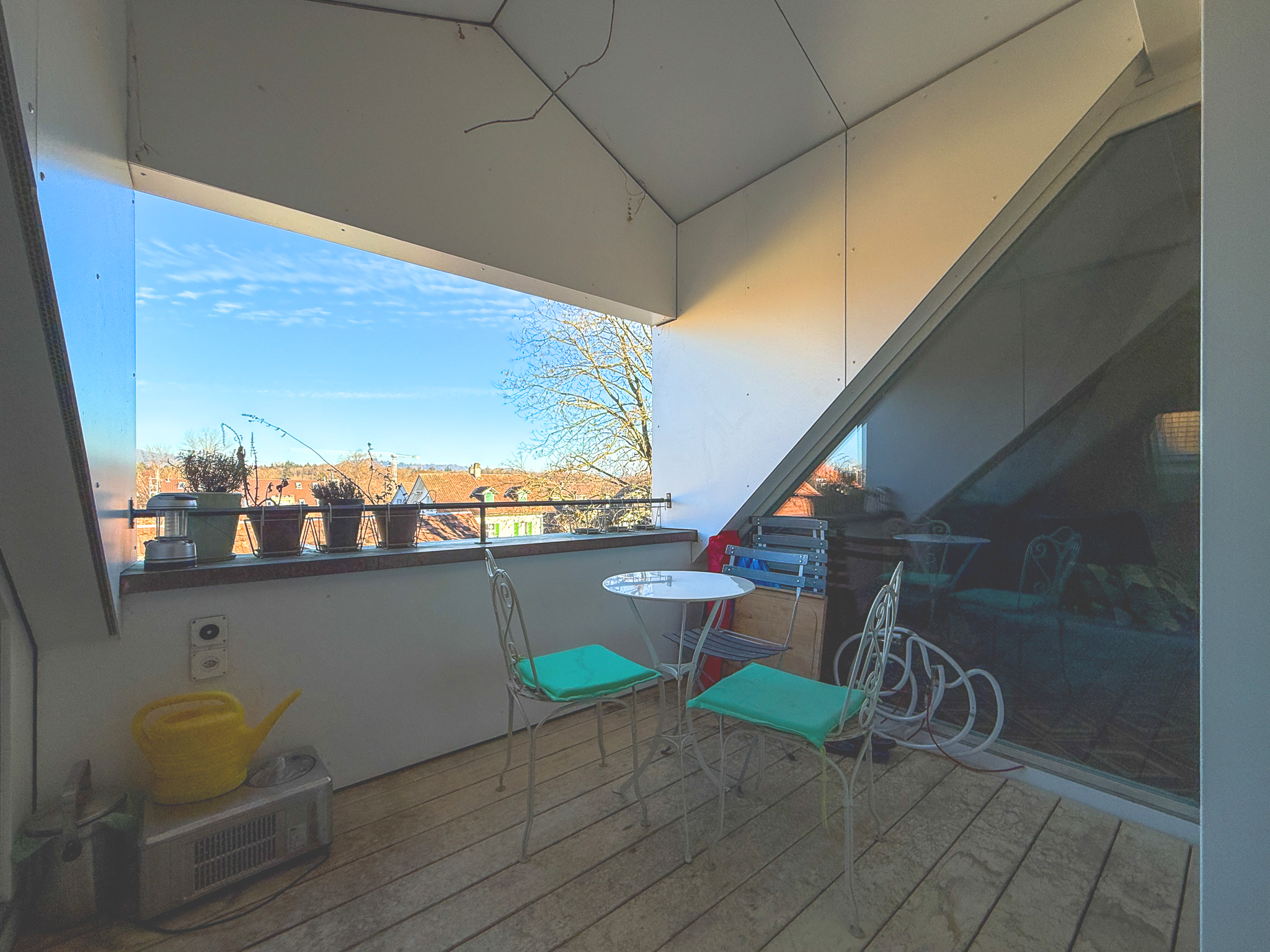 Überdachter Balkon mit Blick ins Grüne und auf Nachbarhäuser