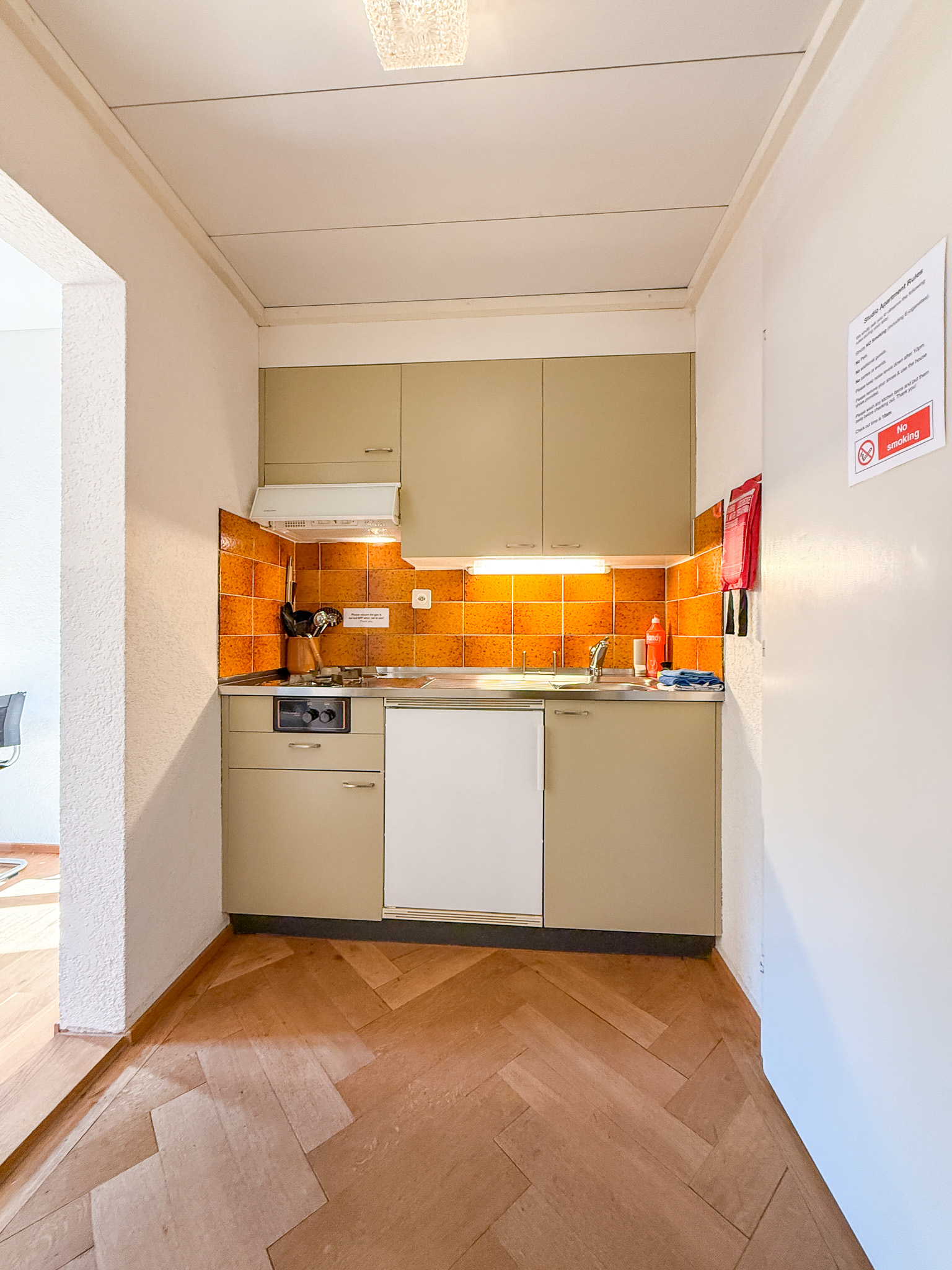 Kleine Küchenzeile mit orangefarbener Rückwand