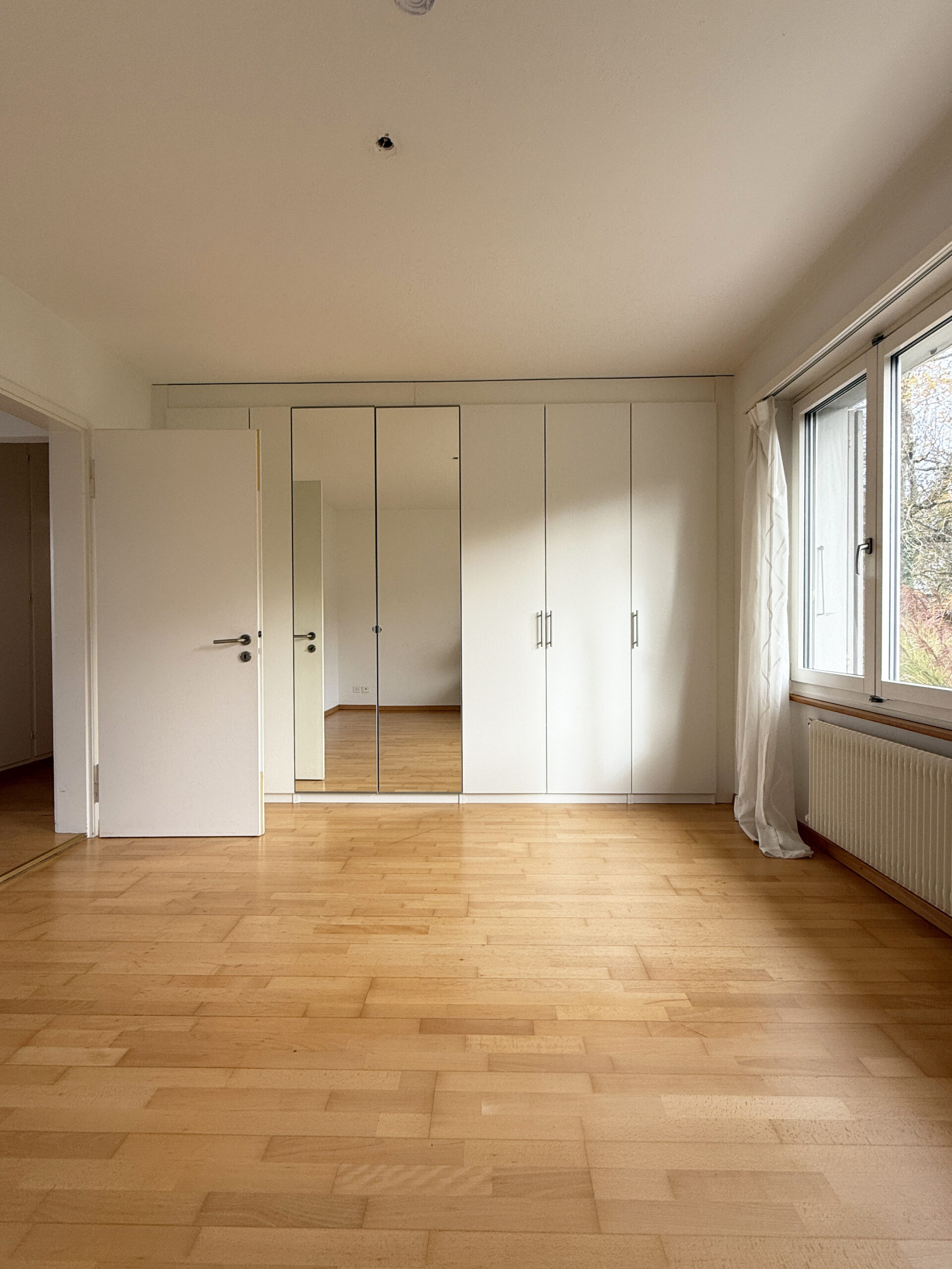 Helles Schlafzimmer mit Einbauschrank und Fenster