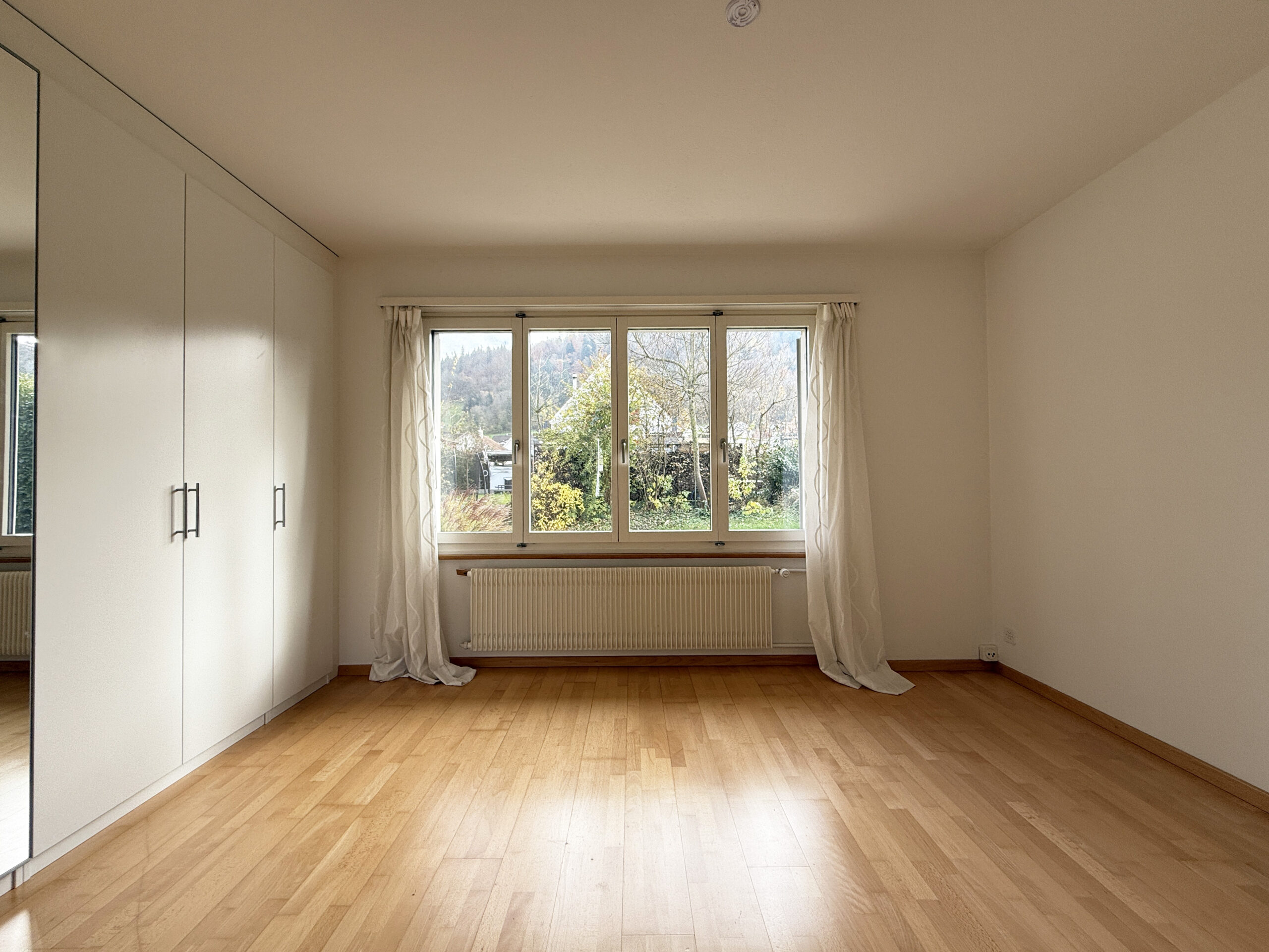 Helles, leeres Schlafzimmer mit Fenster und Einbauschrank