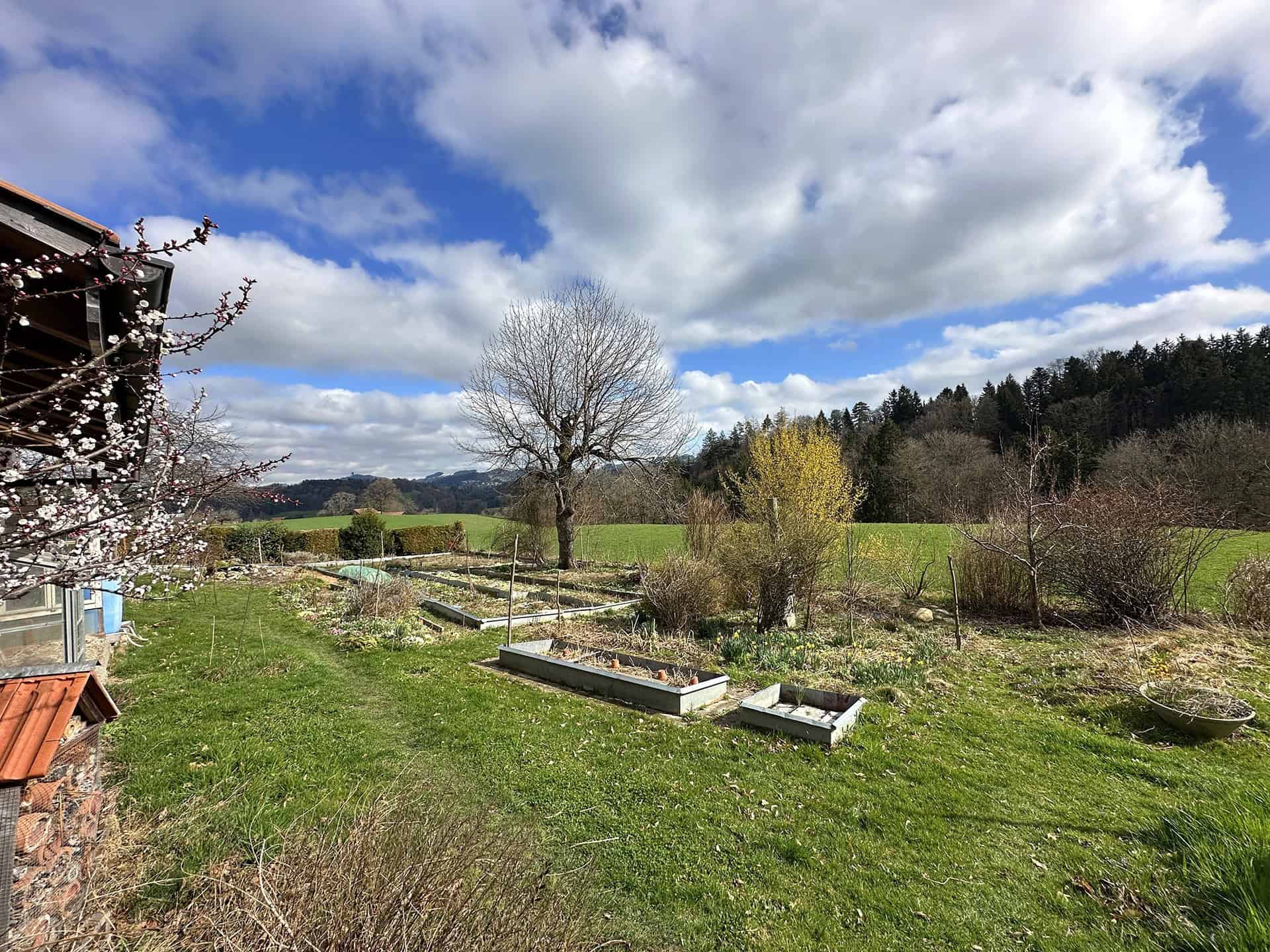 Ländlicher Garten mit Beeten und Talblick