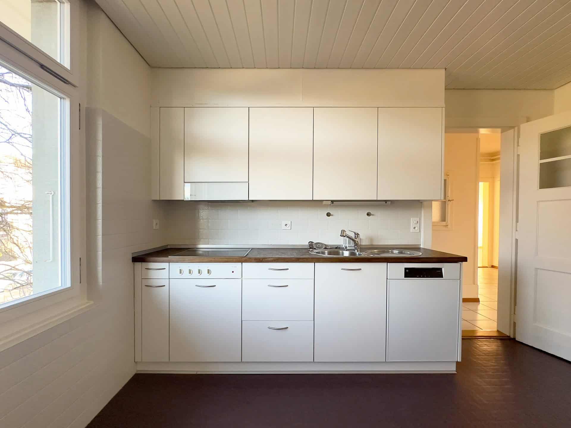 Kleine helle Küche mit weißem Einbauschrank